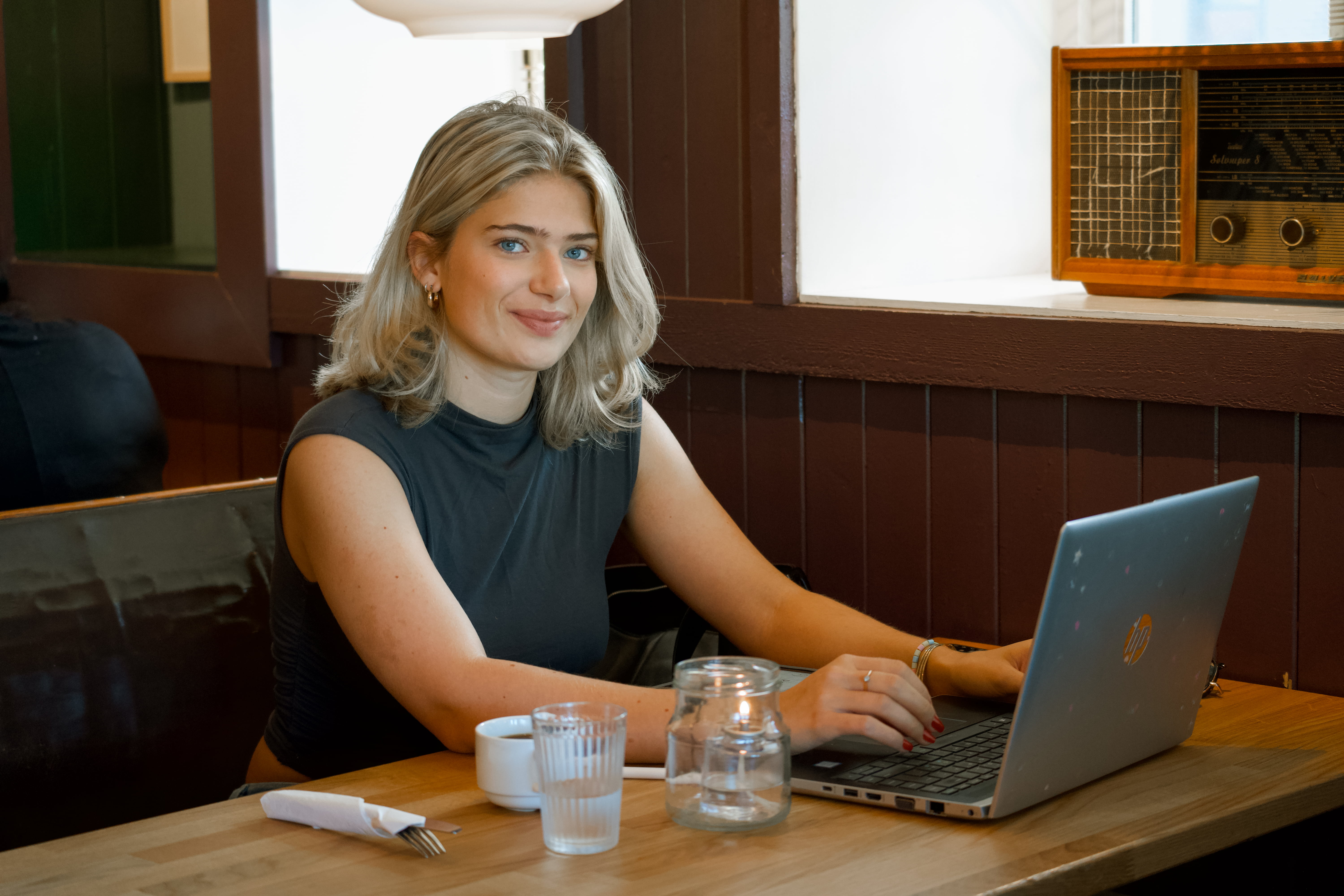 Jente i tyve-årene på cafe med en PC foran seg