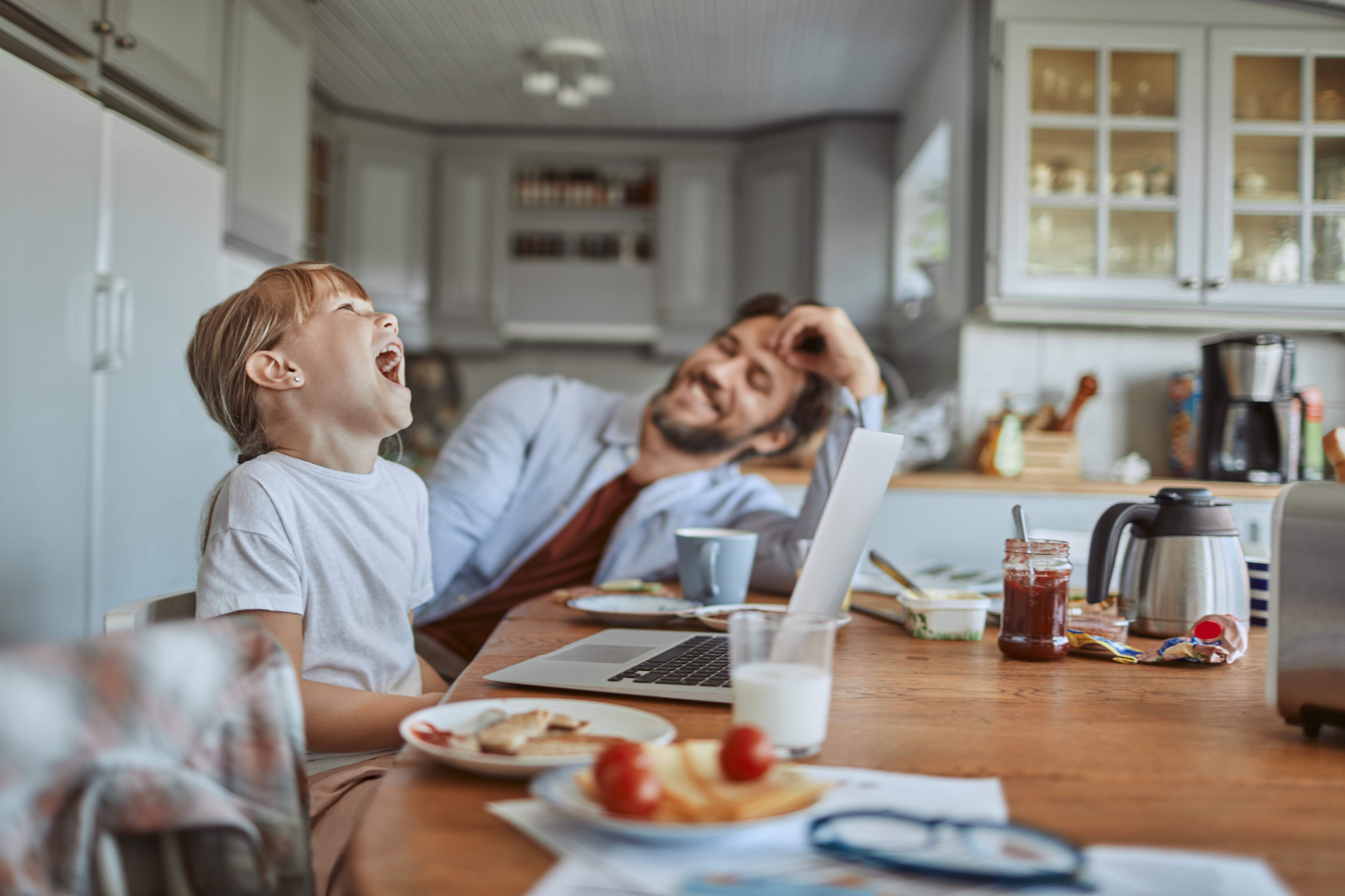 jente og pappa ler rundt frokostbordet