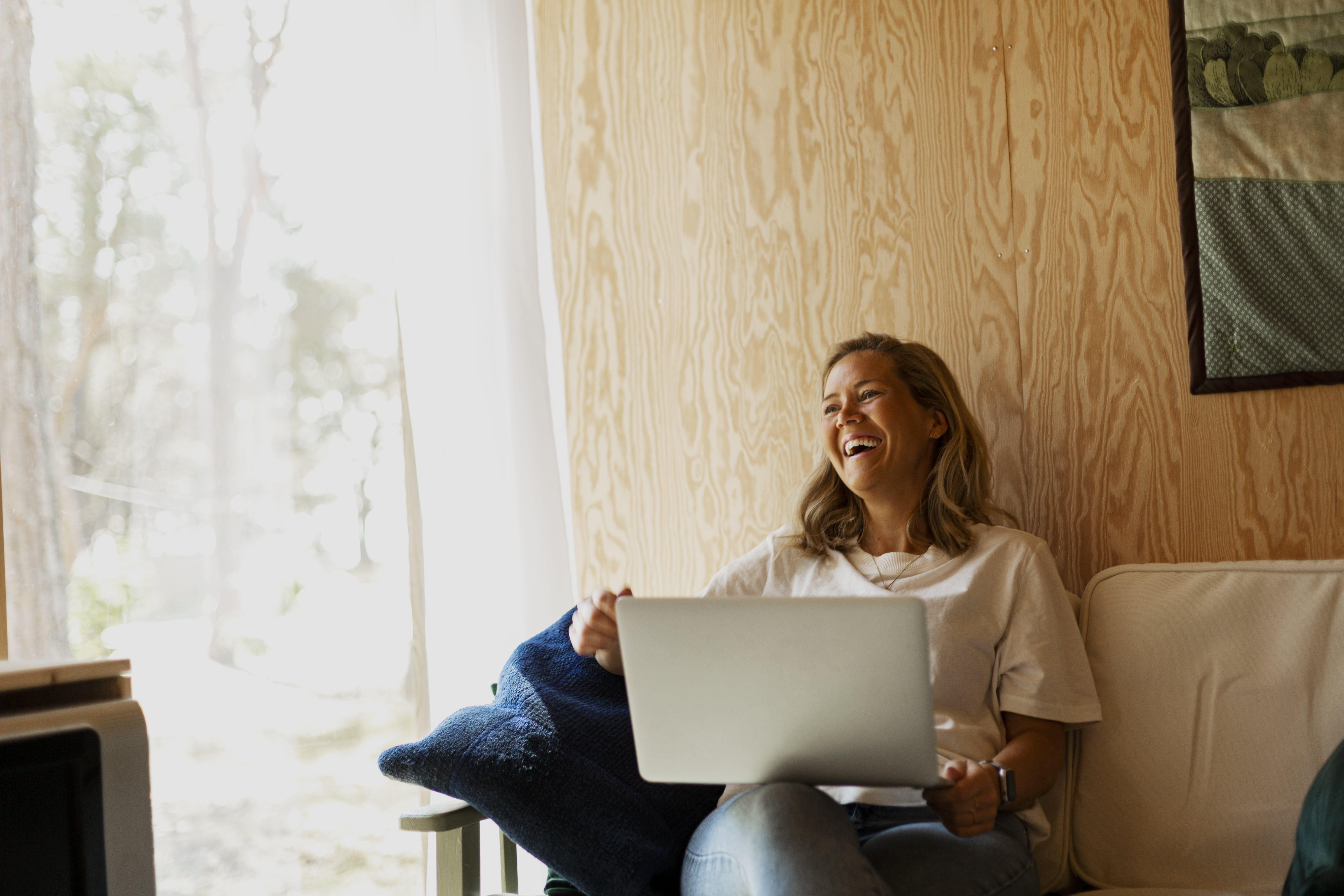 En smilende dame som sitter foran er pc 