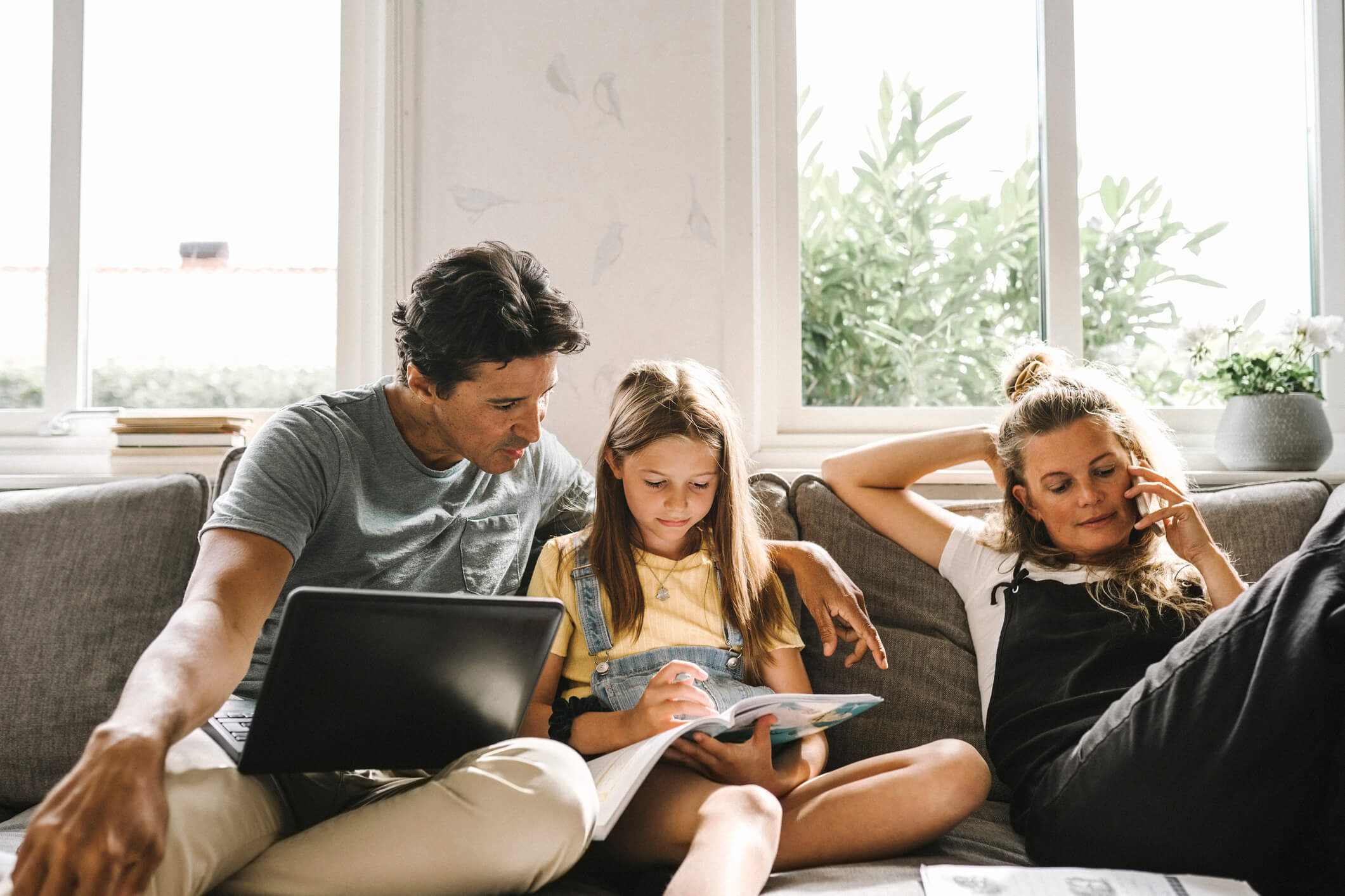  En familie sitter i sofaen og ser på nettbrett