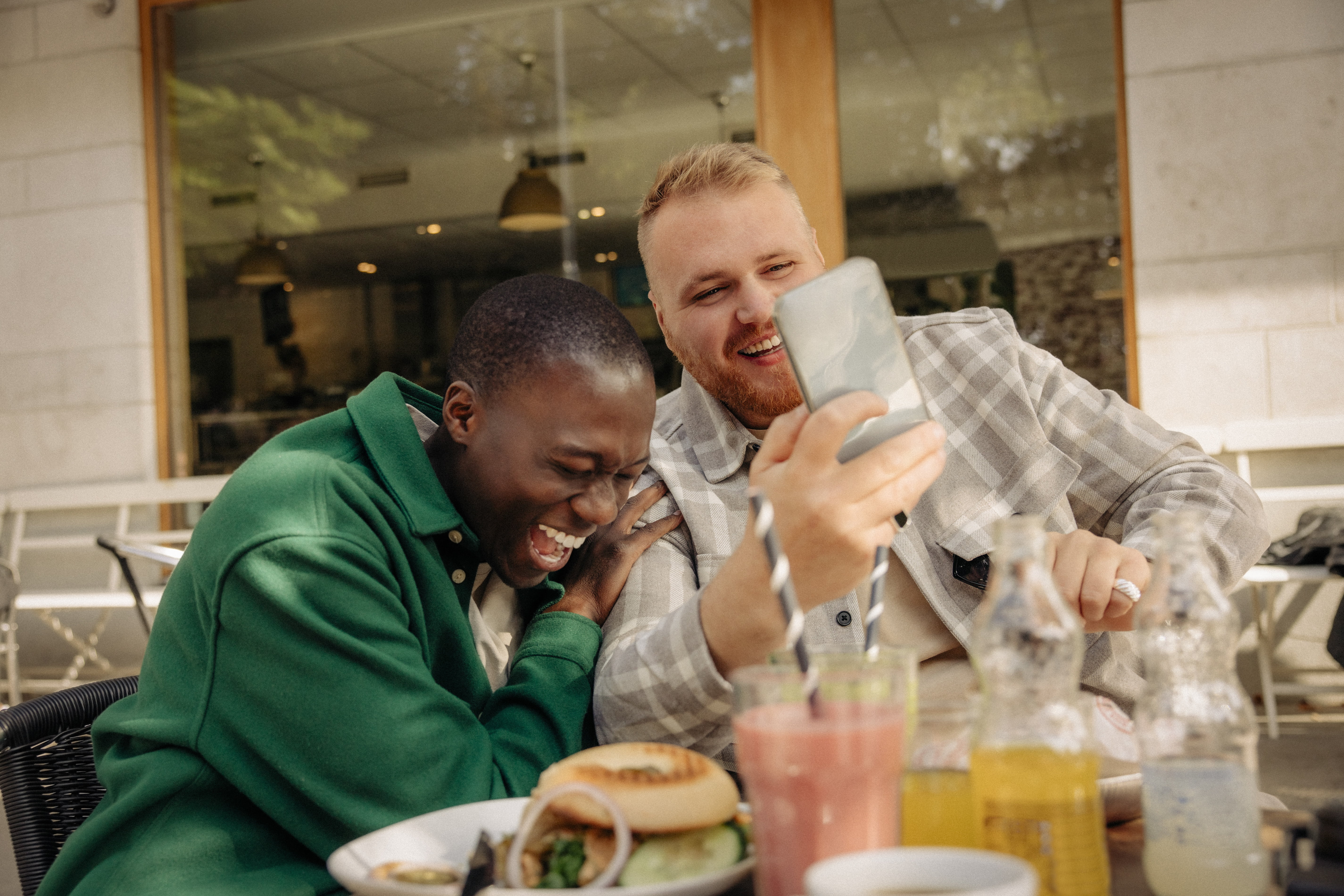 To gutter sitter på en restaurant med mobil og smiler og ler